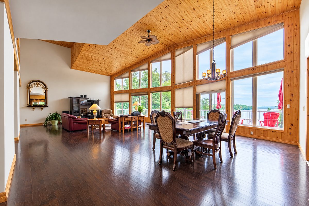 Clubhouse: the great room dining table under a pine ceiling, with tall windows onto the lake