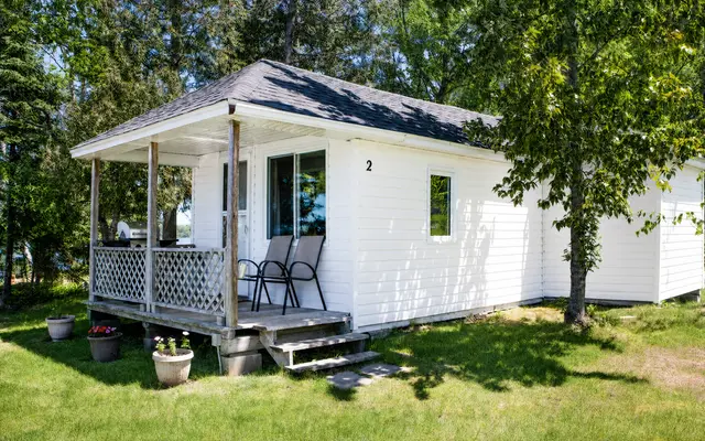 Lucky Duck, a white cottage with a covered porch among the trees