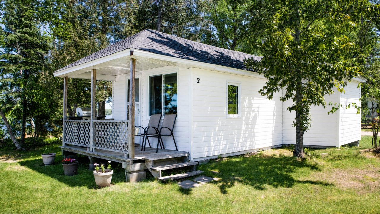 Cottage 2 beyond a green lawn at Cozy Camp