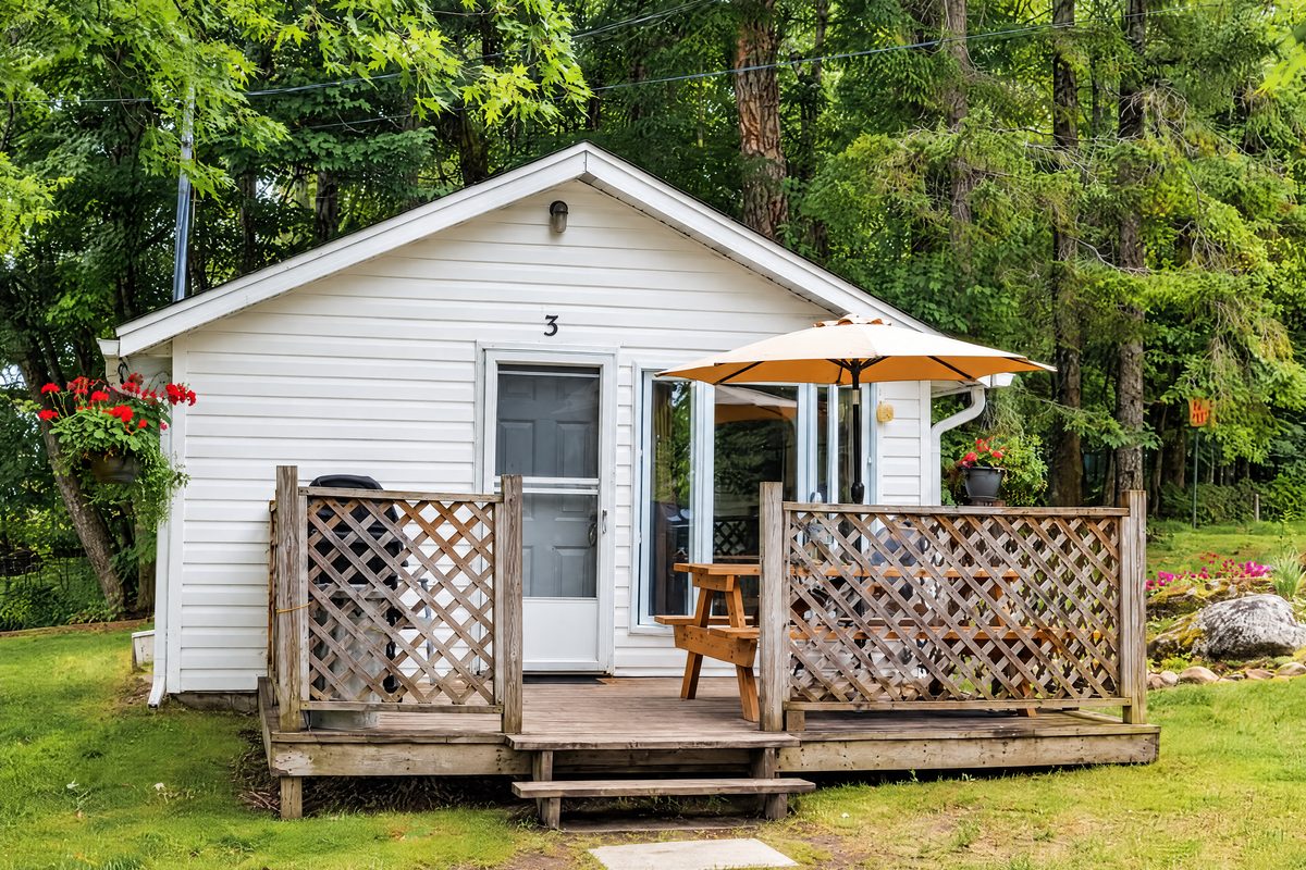 Little Gem, a white cottage with a fenced deck and a patio umbrella