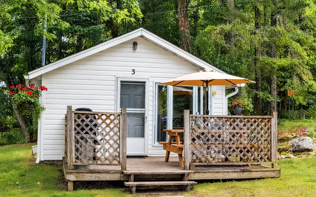 Little Gem, a white cottage with a fenced deck and a patio umbrella