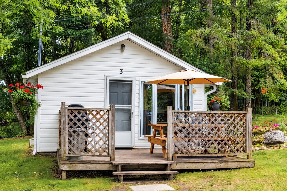 Little Gem, a white cottage with a fenced deck and a patio umbrella