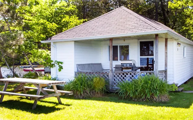 Peaceful Point, a white cottage with a covered porch and a picnic table