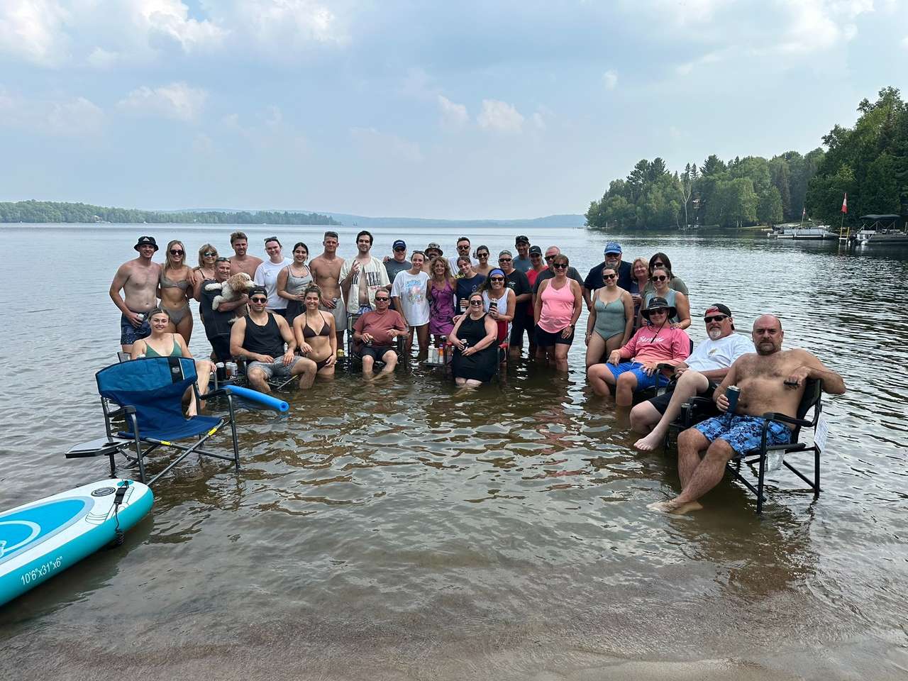 A large group of family and friends gathered in the shallow lake water beside the beach