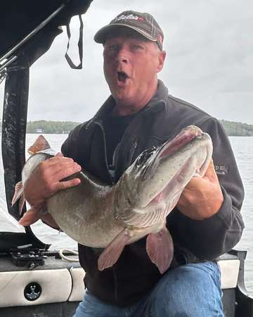 An angler holding a large fish aboard a boat