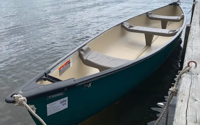 A green canoe tied alongside the dock