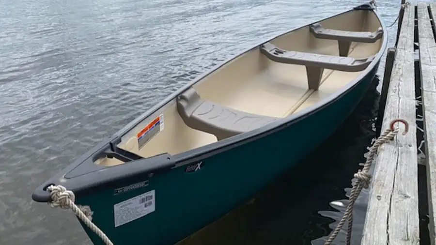 A green canoe tied alongside the dock