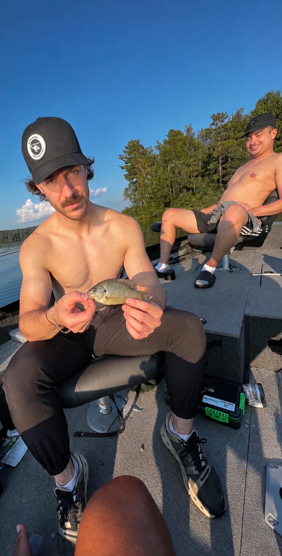 Two friends on a boat, one holding a small fish