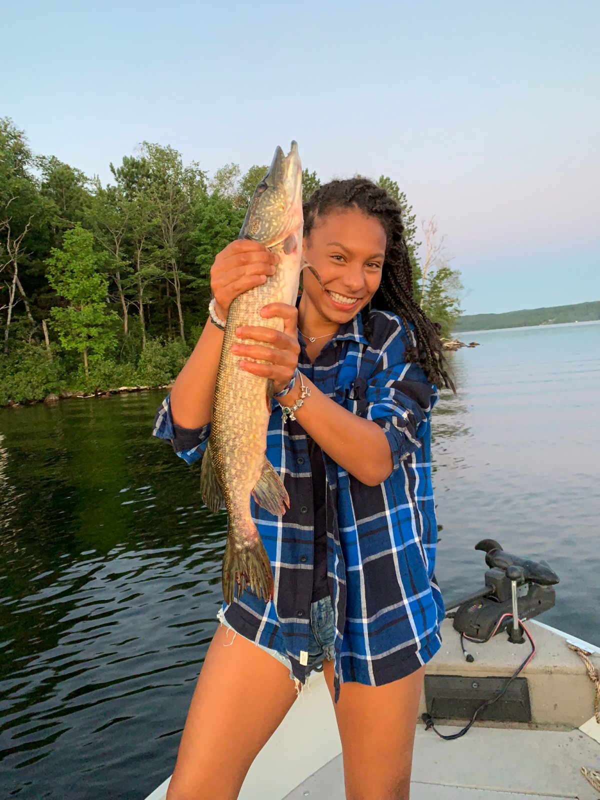 A smiling woman holding a long fish on a boat