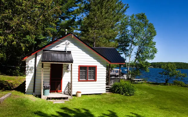 Loon Landing, a white cottage with red trim, with the lake behind it