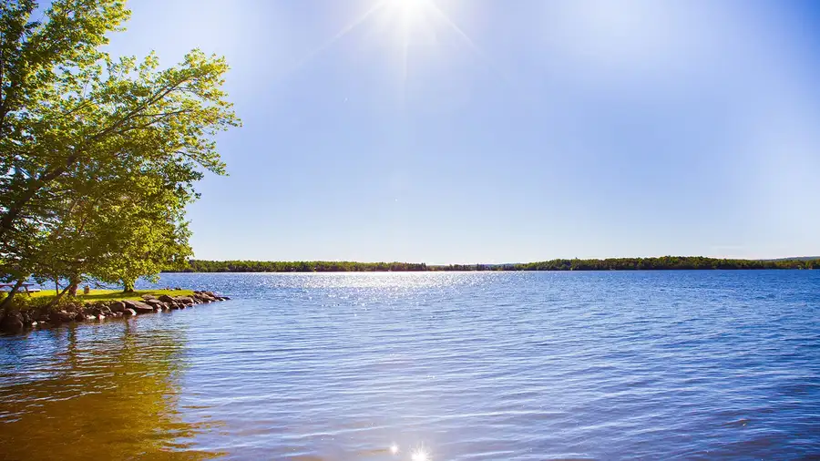 Sun over calm water on Lake Nosbonsing, seen from the shore at Cozy Camp